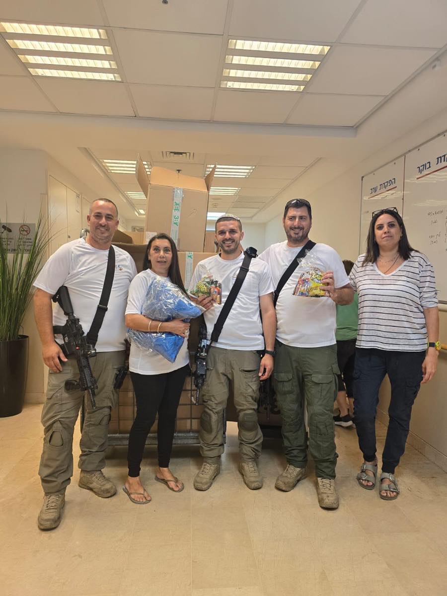 צוות מתנדבי העמותה עומד יחד עם אנשי כוחות הביטחון אחרי חלוקה