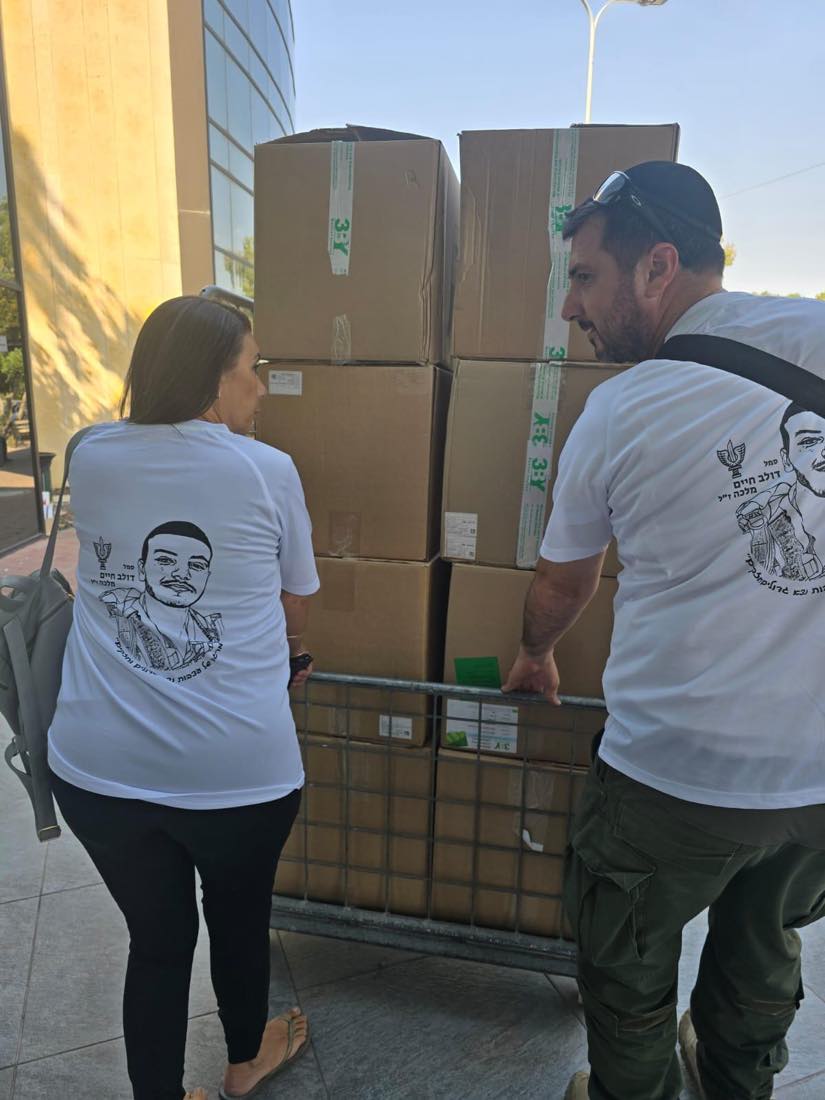 מתנדבי העמותה מעמיסים קרטונים ארוזים לפני יציאה לחלוקה